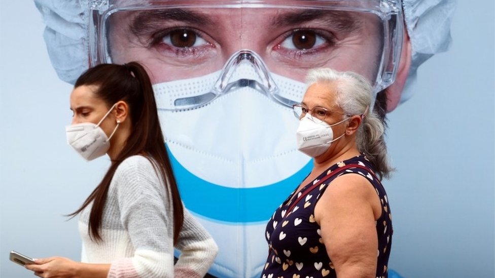 People, wearing protective face masks, walk past a dental clinic advertisement at Vallecas neighbourhood in Madrid, Spain, September 18, 2020.