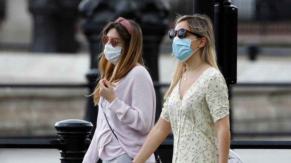 Two women walking wearing face masks