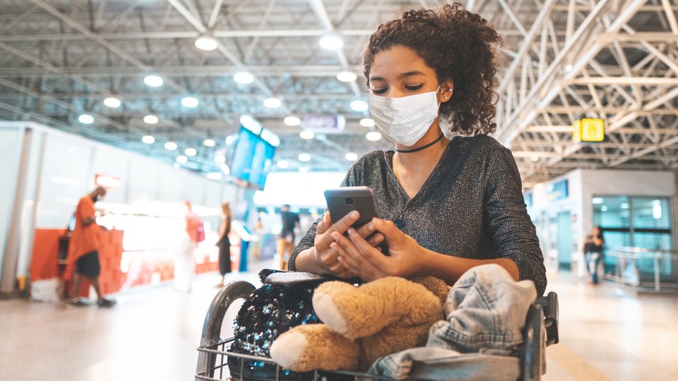 A girl looking at her phone in the airport (stock image)