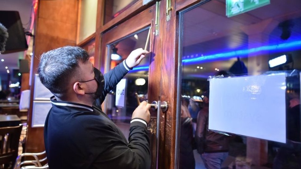 A worker shuts the doors in a bar in Bristol city centre, ahead of a national lockdown for England from Thursday
