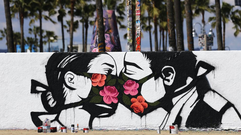 A graffiti of a couple wearing facemasks kissing
