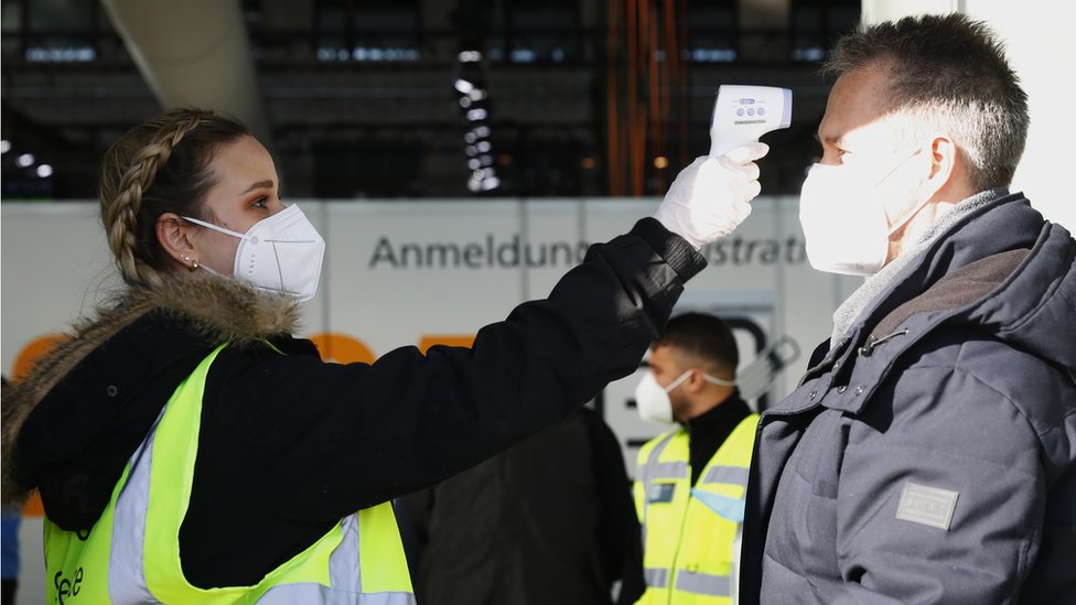 A Volunteer checks the temperature of a police officer in Hangar 4 of former Tempelhof Airport, Berlin
