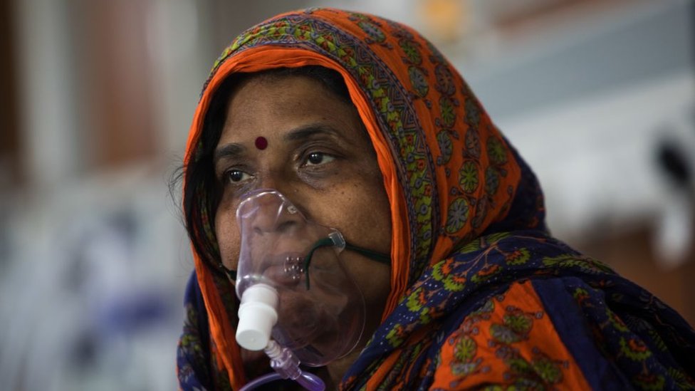 A COVID-19 coronavirus patient sits on her bed at the Intensive Care Unit of the Sharda Hospital, in Greater Noida