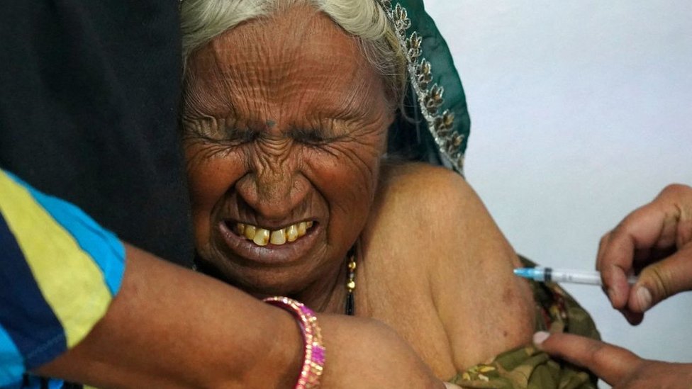 An elderly woman reacts as she is inoculated with the Covid-19 coronavirus vaccine at a government hospital on the outskirts of Ajmer