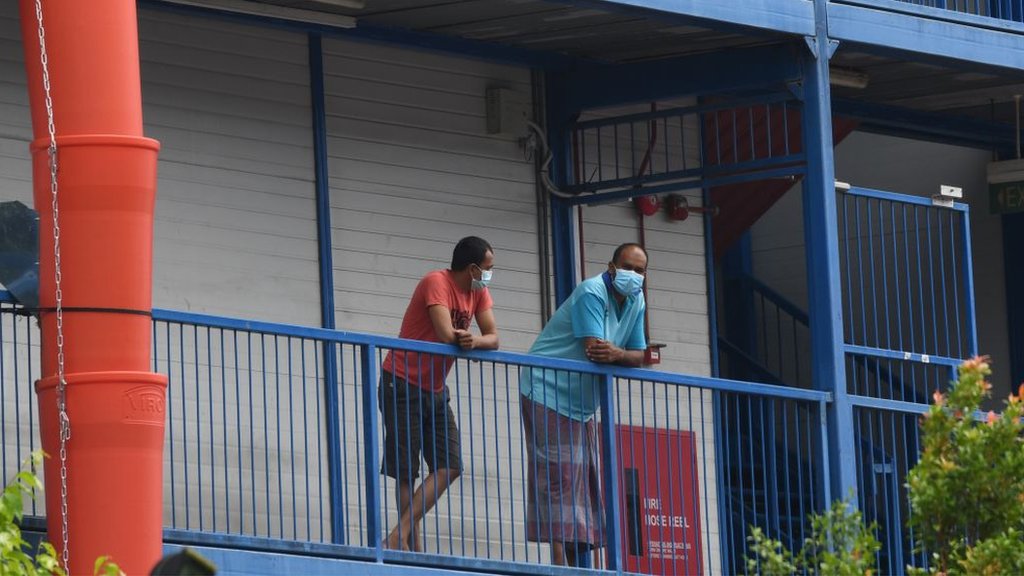 Migrant workers wearing face masks as prevention for the spread of the COVID-19 coronavirus look out from a quarantined dormitory building in Singapore on 20 May 2020.