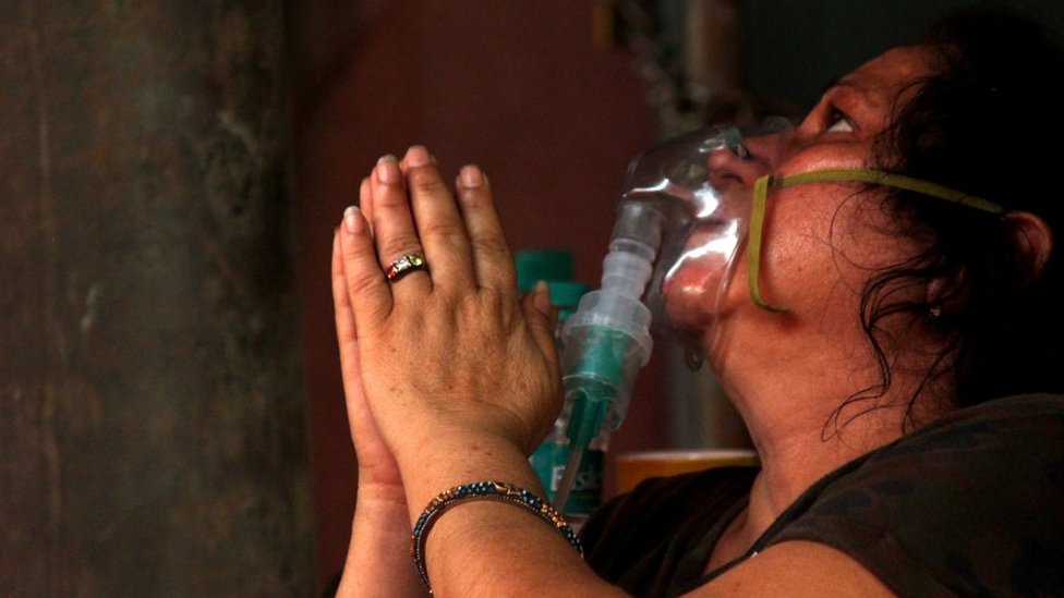 A woman with an oxygen mask on prays
