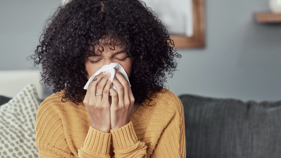 A woman coughing into a tissue