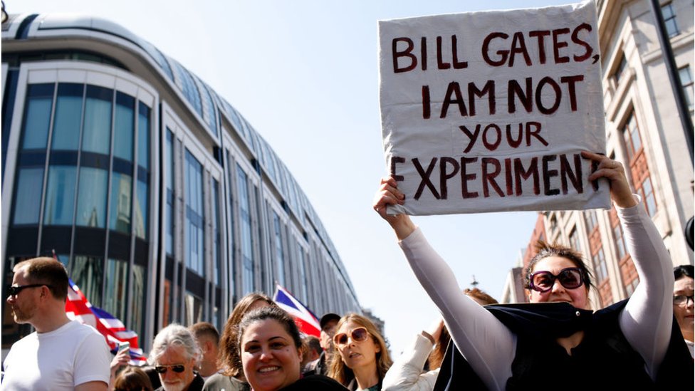 Woman holds sign about Bill gates at protest