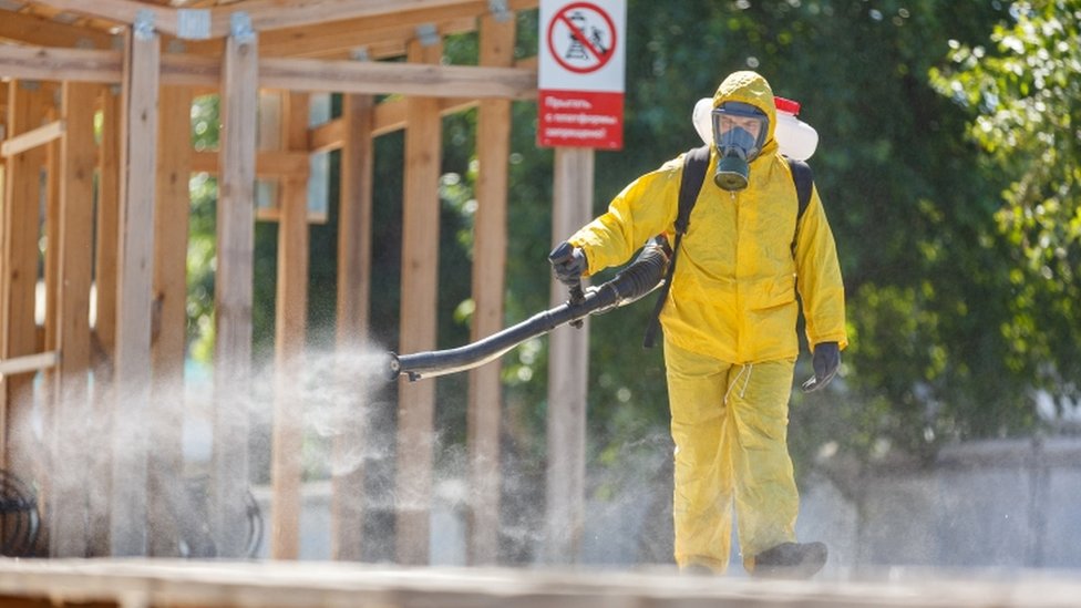 A specialist wearing personal protective equipment sprays disinfectant while sanitising a railway station in Moscow