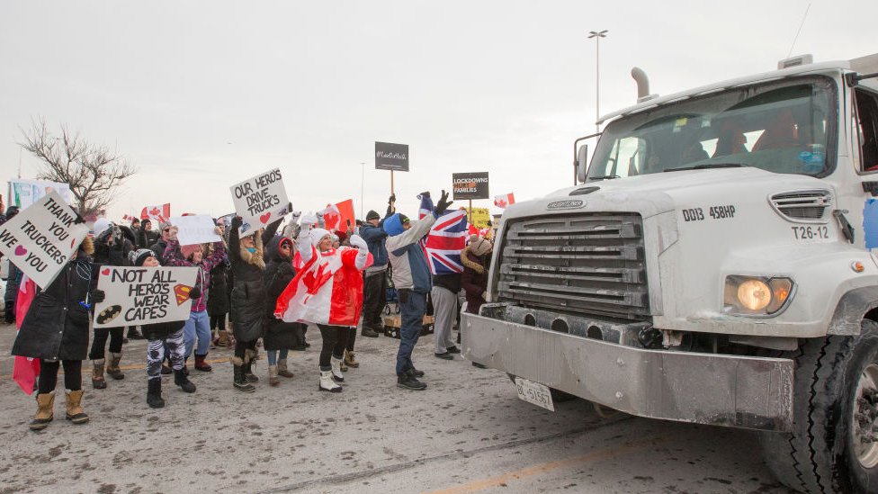 A truck is greeted as it passes by some of those who gathered to show support for the cross country truck convoy.