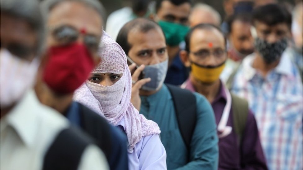 People wearing protective masks wait in line to board a bus amidst the spread of the coronavirus disease (COVID-19) in Mumbai, India, October, 6, 2020
